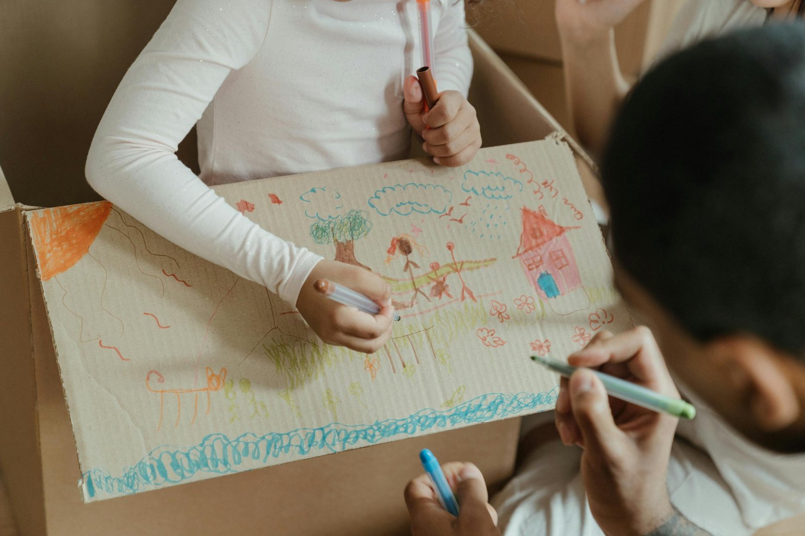 Kids enjoying creative time drawing on a cardboard box during a home move.