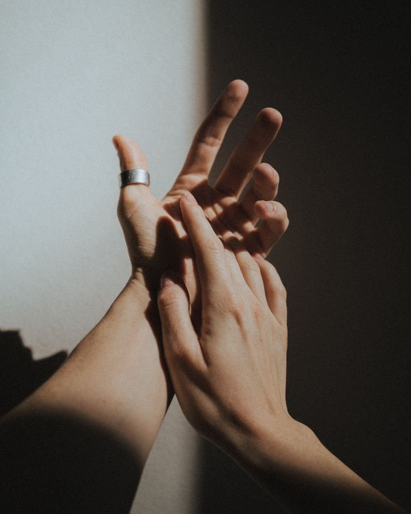 A detailed close-up of hands, one adorned with a ring, skillfully playing with light and shadows.
